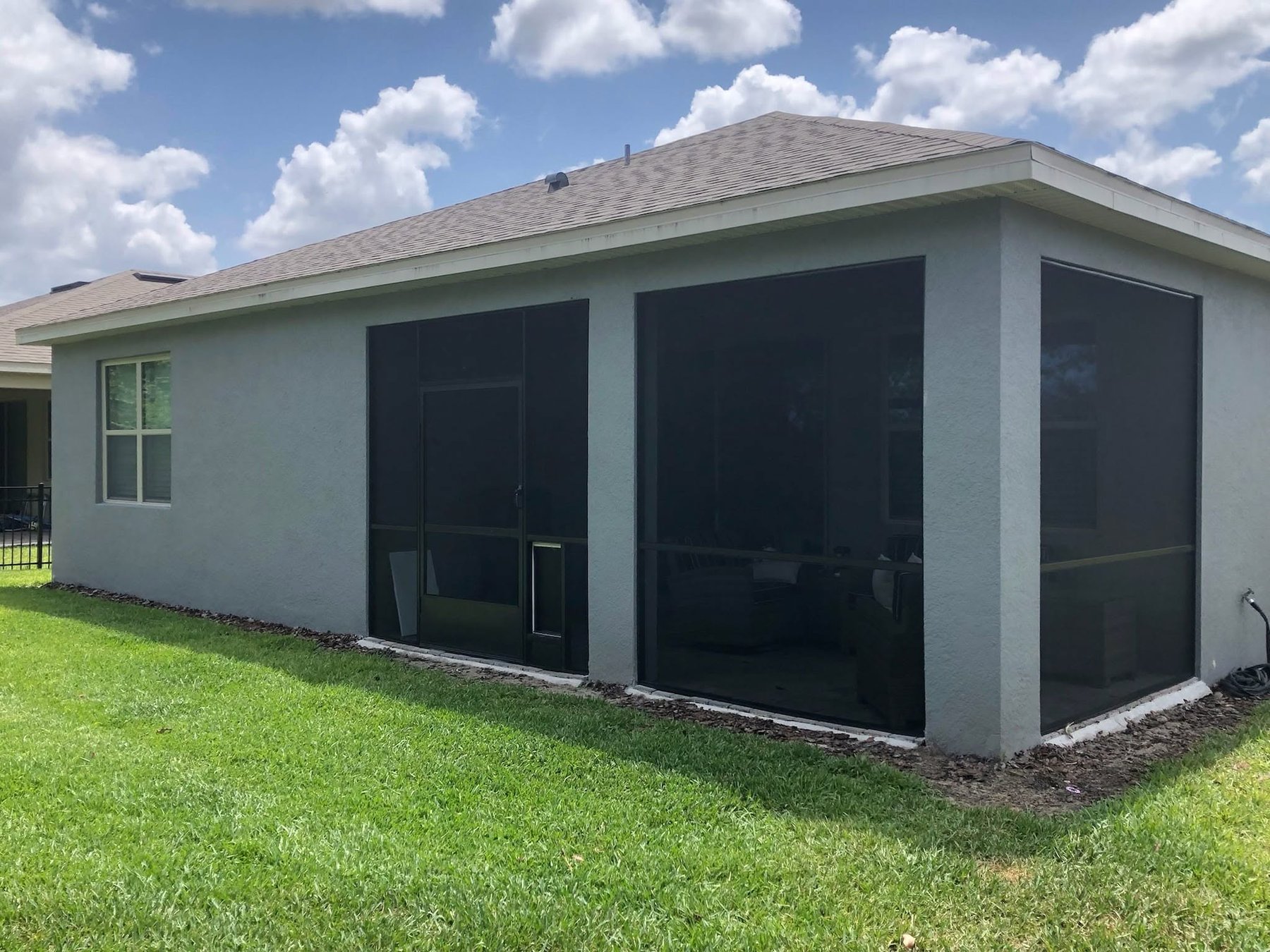 Finished screened sunroom addition with dark aluminum frame after installation