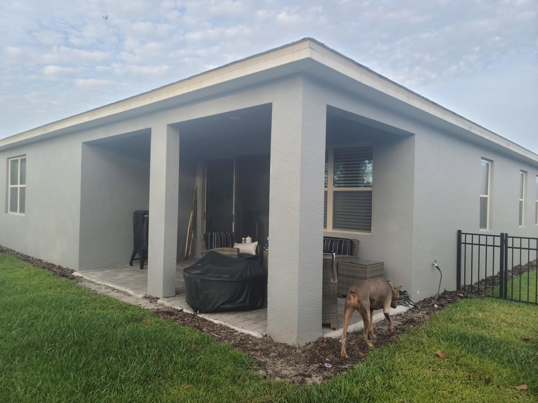 Open covered patio with support posts before screened sunroom addition