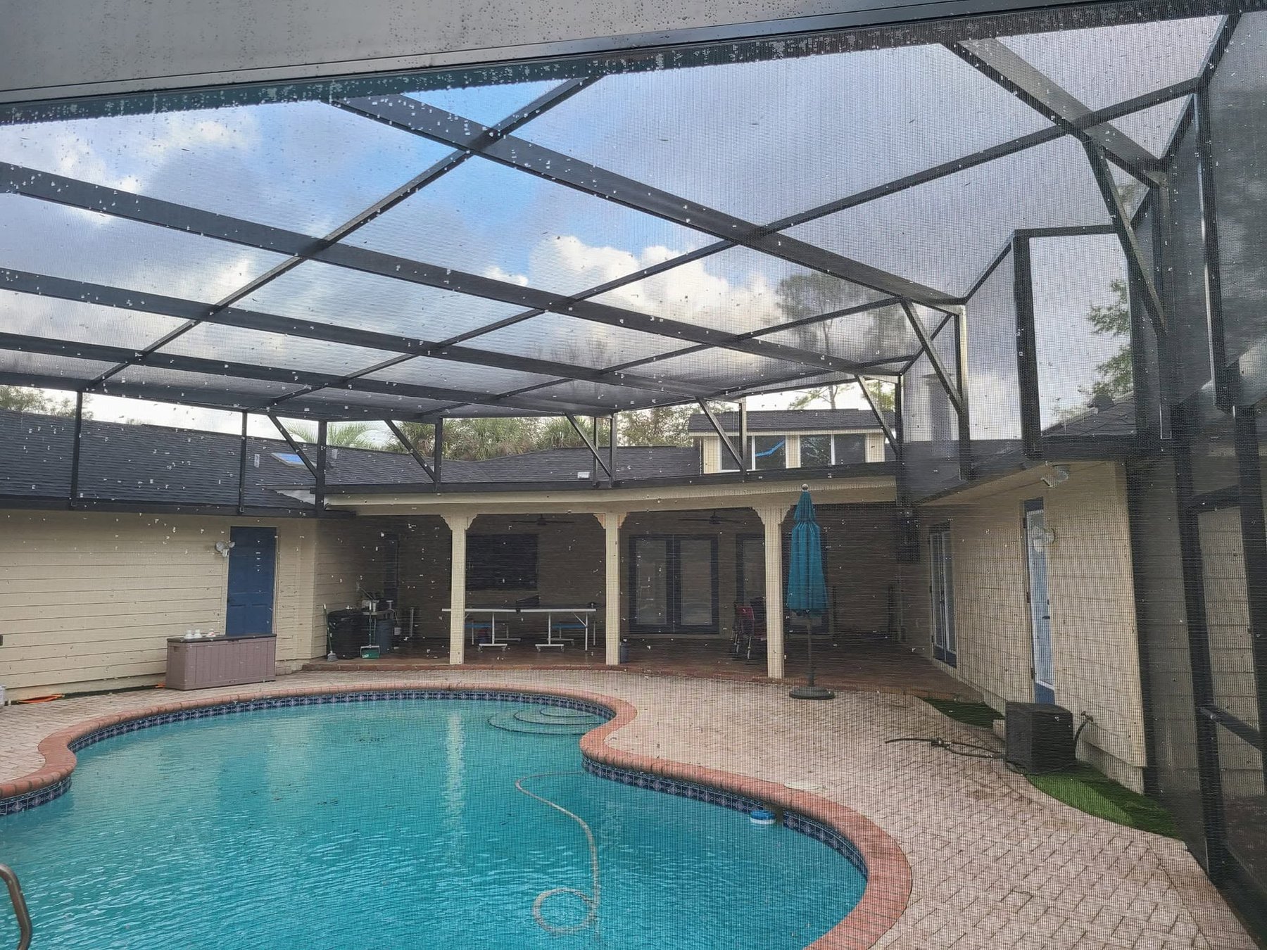 Screened pool enclosure with clear blue sky over paver patio and pool