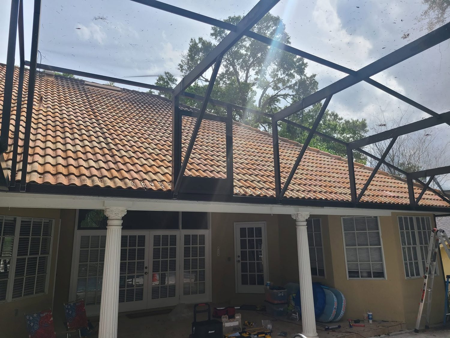 Screen enclosure roofline against terracotta tile roof and oak trees