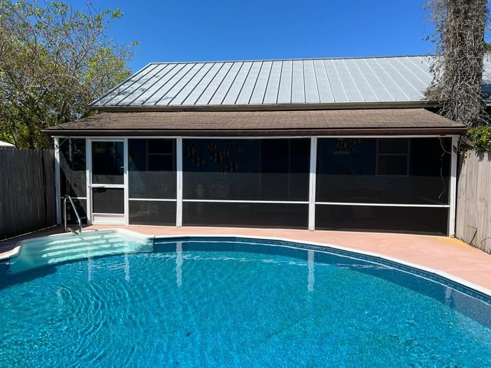 In-ground pool with blue tile trim inside existing screen enclosure