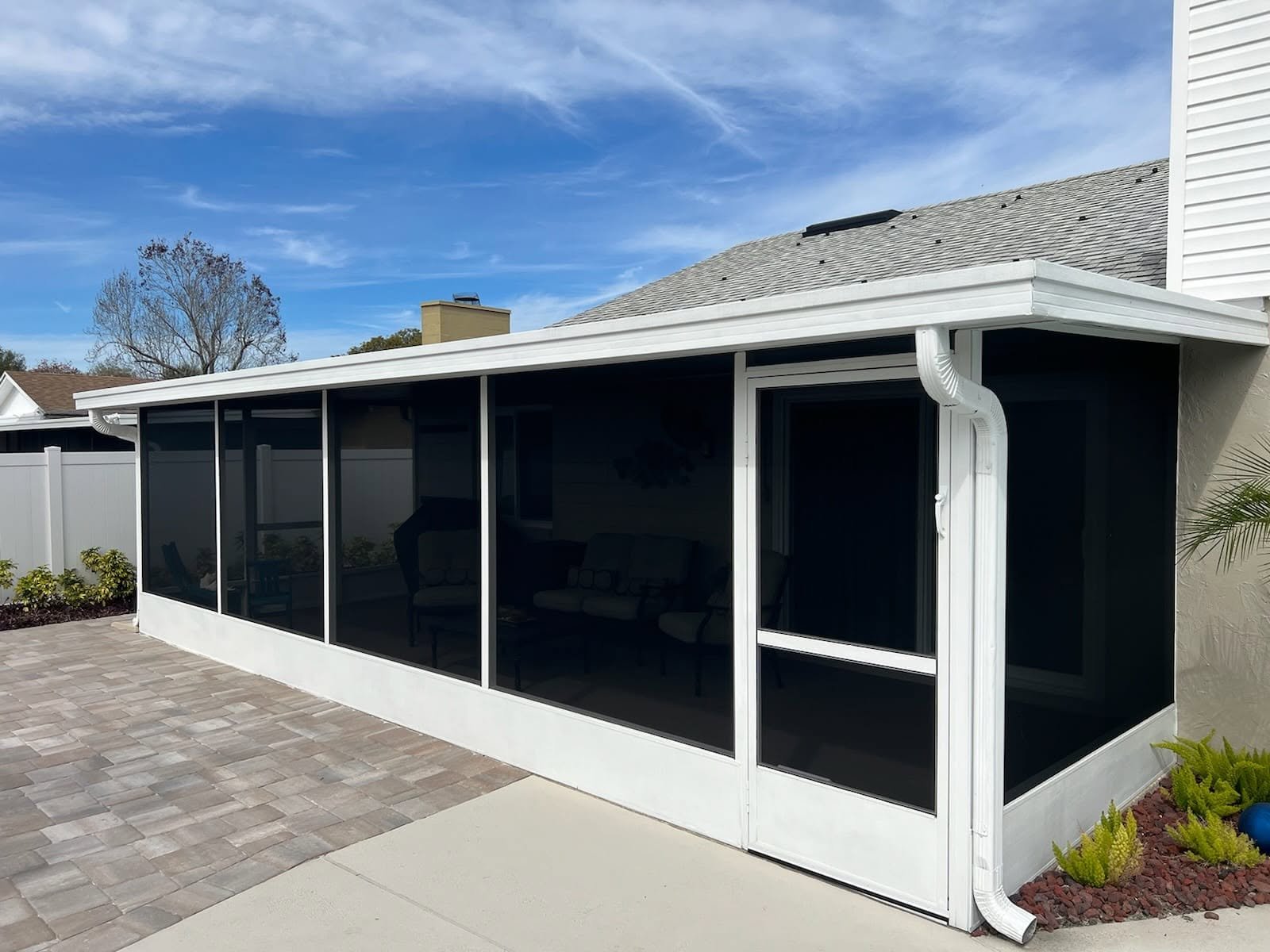 White-framed screened sunroom addition with new gutter and shingle roof